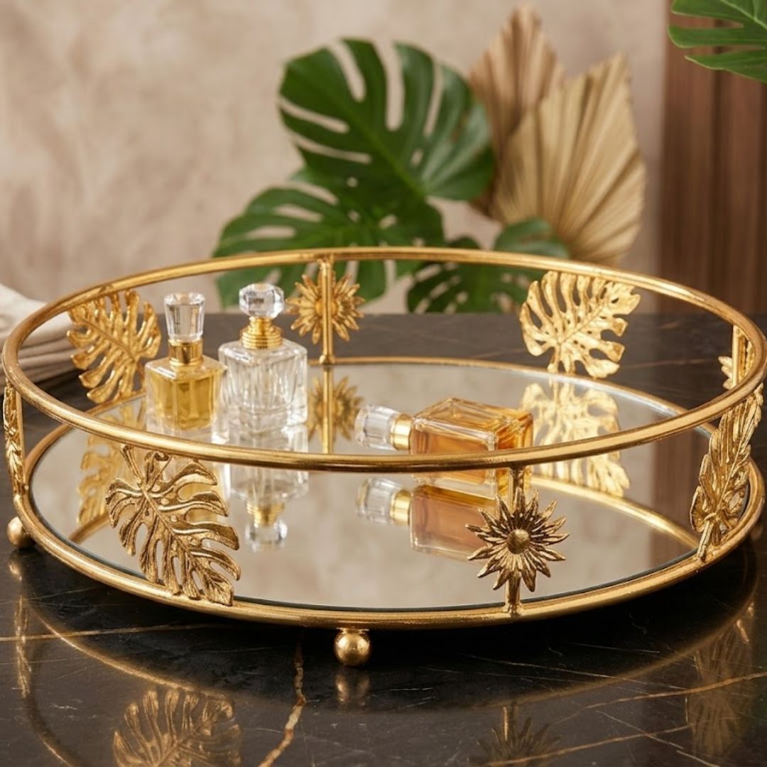 luxurious round vanity tray features a gold metal frame accented with decorative leaf and sunburst motifs, paired with a mirrored glass surface