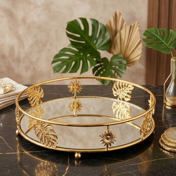 luxurious round vanity tray features a gold metal frame accented with decorative leaf and sunburst motifs, paired with a mirrored glass surface