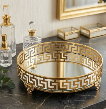 gold metal vanity tray features a distinct Greek key patterned border and a mirrored base