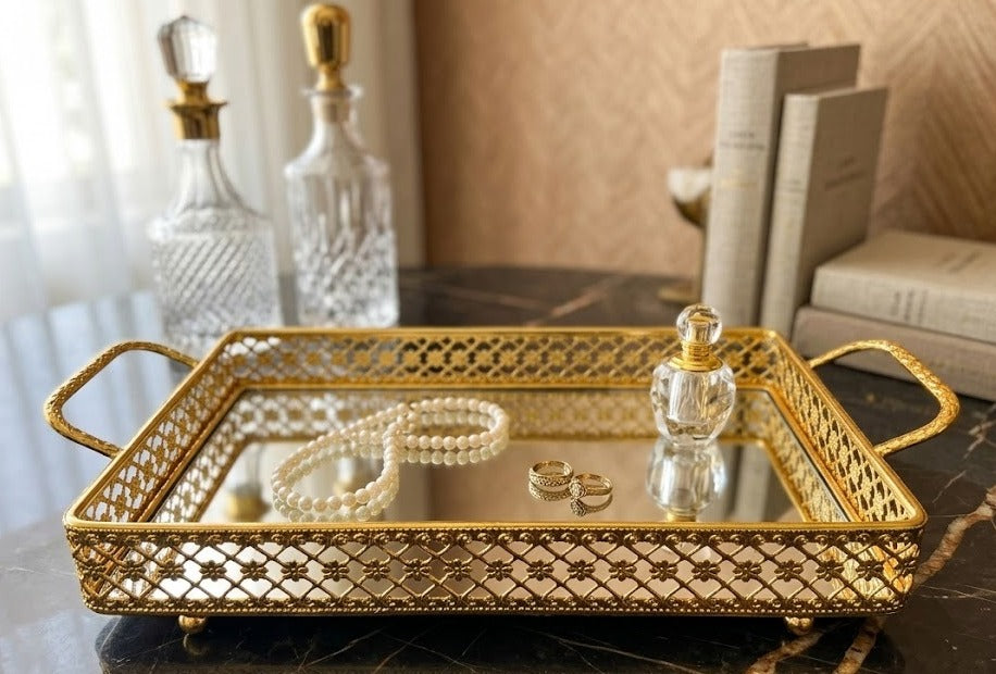 decorative vanity tray features a gold metal frame with intricate filigree cutouts and a mirrored base
