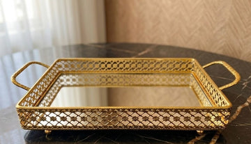 decorative vanity tray features a gold metal frame with intricate filigree cutouts and a mirrored base