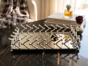 This decorative rectangular vanity tray features a silver-plated frame with a modern geometric desig
